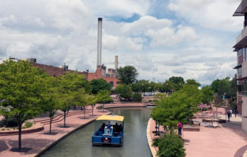 A tourist boat with a bright yellow canopy traveling down to historic Arkansas River Walk near Happy Acres RV Park in Pueblo CO